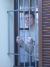 Stephane at the window frowning behind the bars