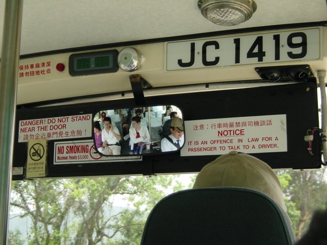 Passengers of a bus view in the rearview mirror