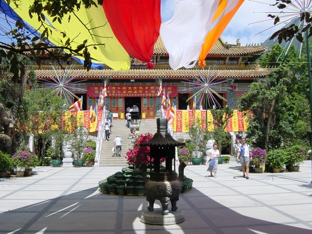Monastery court with incense burner, flags, stairs and other building at the background