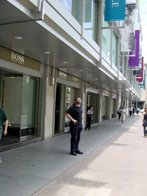 Daniel, the boss, standing in front of a "Boss" shop and looking up