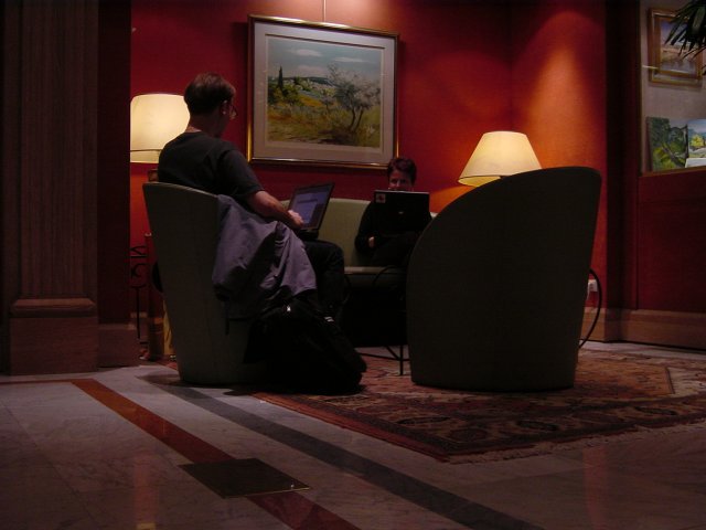 Jose and Irene in the lobby of hotel Plaza, laptops connected