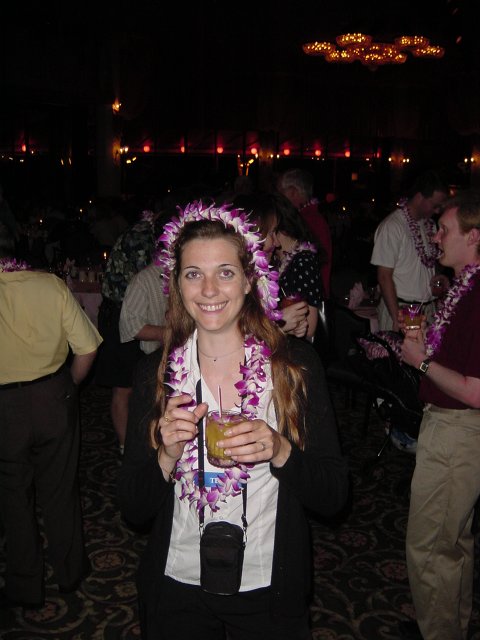 Coralie with a lei on the head and another around the neck, holding a cocktail