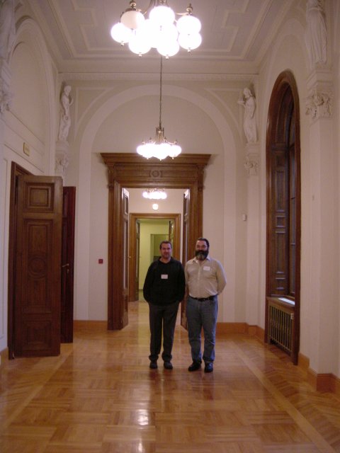 Daniel and Ivan in the hall in front of the event room: wooden floor, high wooden door, carved ceiling, etc.