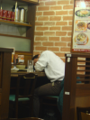 Man sleeping on the table ; the remains of his dinner next to him