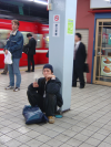 Man sitting on the floor smoking and leaning on a pillar bearing a no smoking sign (Karl in the background)