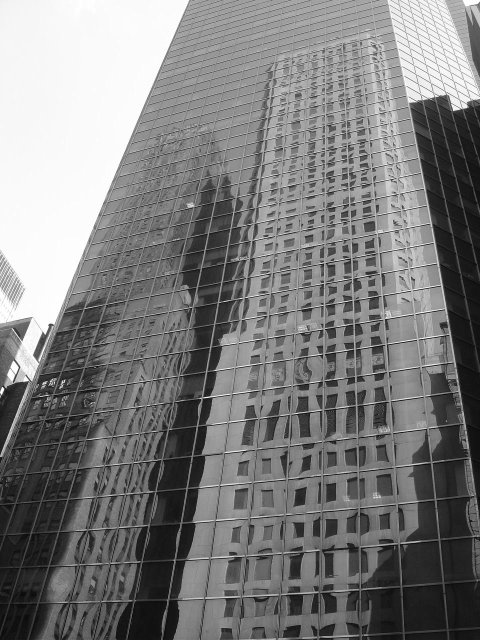 Two tall buildings reflected in a taller one