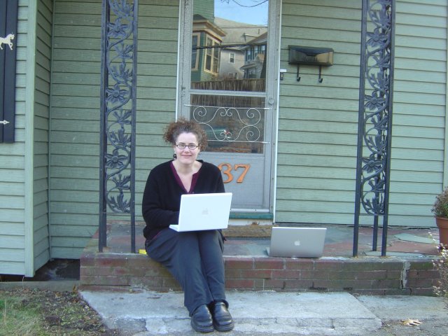 Amy sitting under the porch with her laptop, next to my laptop