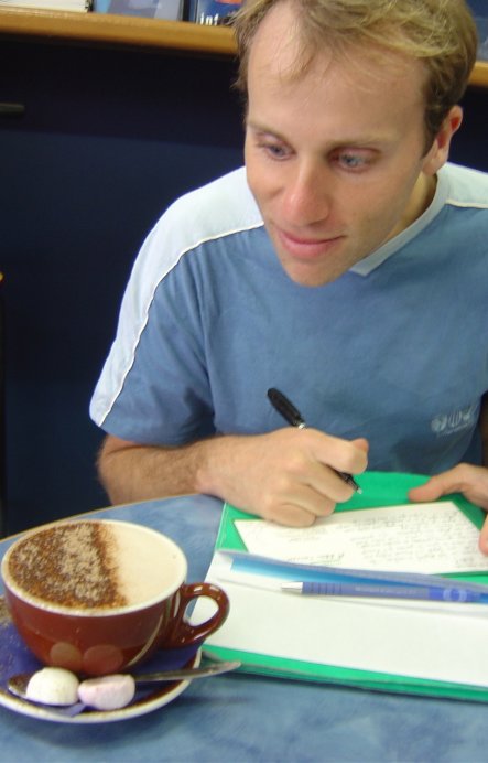 Nico writing postcards and eyeing a hot cocoa intently