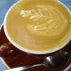 Cup of coffee w/ a fern leaf made w/ cream