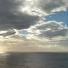 Tasman Sea, dark grey water, dark clouds, blue sky behind and a surrealistic patch of light on the water