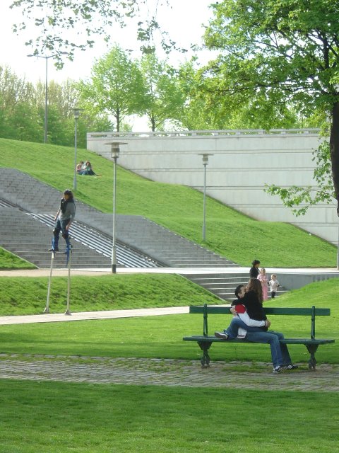 Man on stilts, couple on a bench