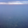 View from the plane on a distant city, haze and dripping clouds