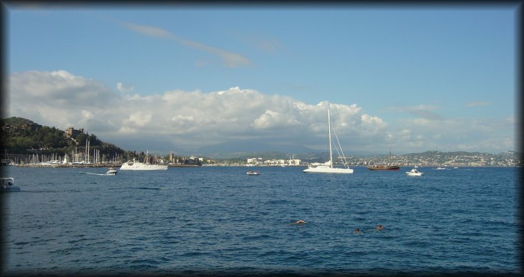 People swimming, boats moored, Cannes in the background