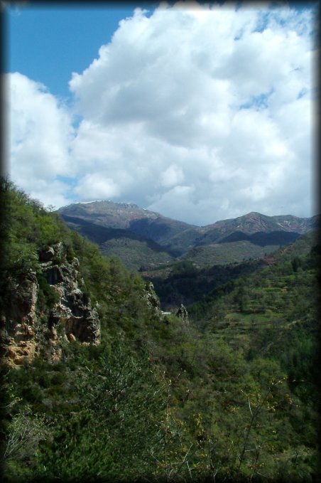 Some rocks, mountains, more mountains, a little snow at the top, clouds and a very blue sky