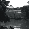 Black and white photo of a couple sitting by the pond in front of the Palacio de Cristal