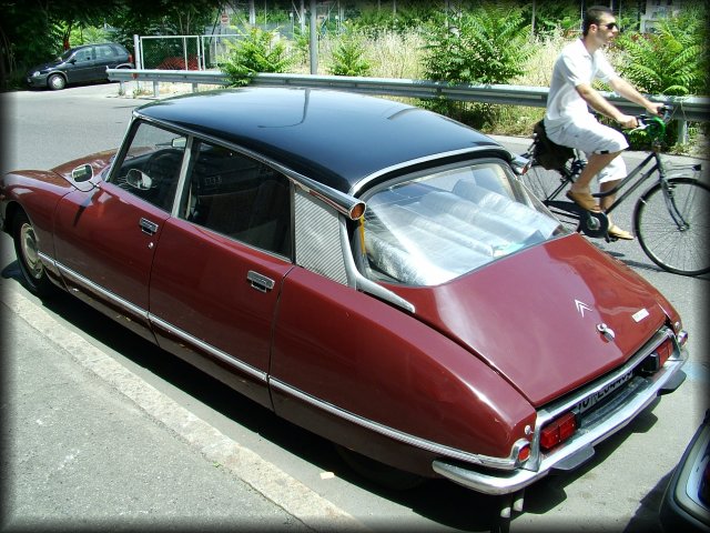 A Citroen DS and a guy on a bicycle passing by.