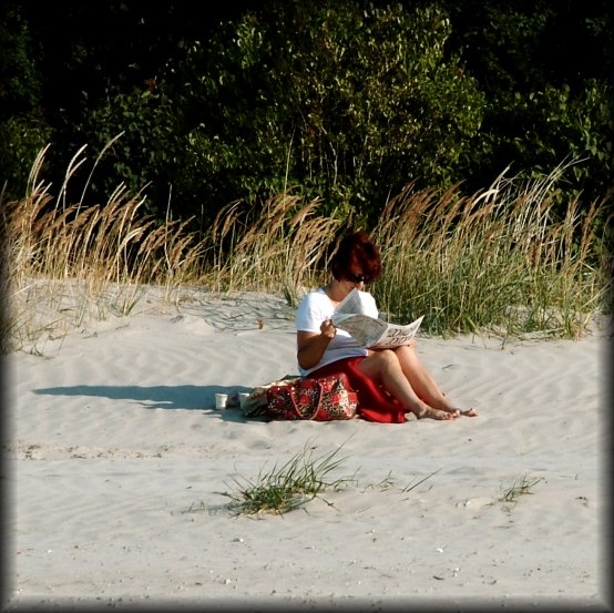All by herself... on the sand, in the sun, with her paper