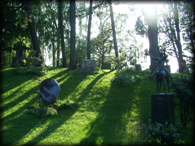 A green mound in the Helsinki cemetery and the sun casting long shadows.
