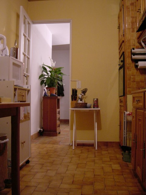 Vue du fond de la cuisine: bout de la table, micro-onde, tablette et vue sur le meuble a telephone