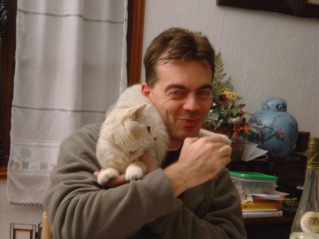Stephane boit son the', impassible avec le chat installe' sur son epaule et son bras