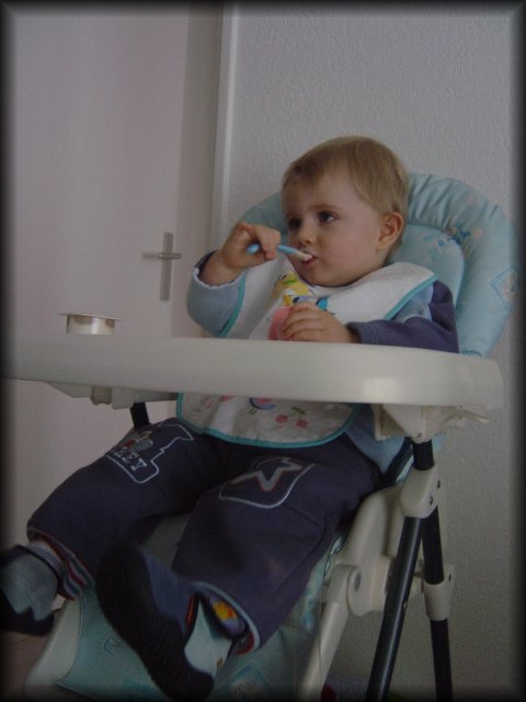 Alexis on his chair eating his yoghurt and looking rather distracted
