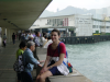 Christelle sitting on a low wall by the harbour