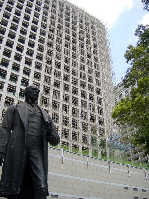 Bronze statue in front of a huge building being renovated