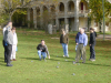 Yves crouching and pointing at a boule, his group around