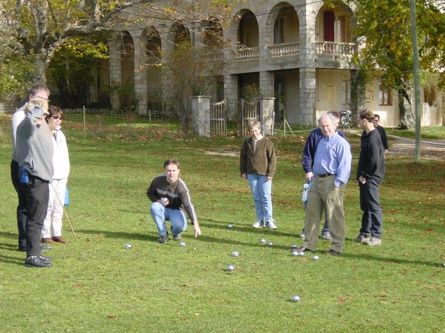 Yves crouching and pointing at a boule, his group around