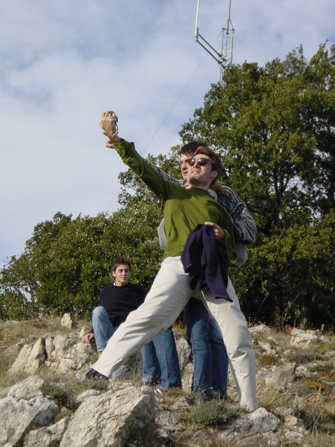 Karl holding his camera in front of his and Philippe's faces, Olivier watching amused from behind