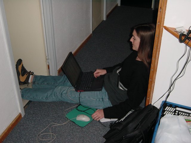Coralie bloquant le couloir, pieds dans les WC, laptop sur les cuisses
