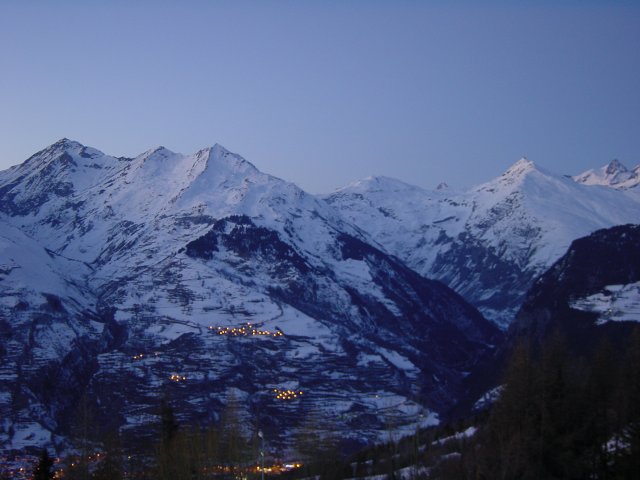 Luminosite bleutee sur les monts enneiges, quelques lumieres de villages