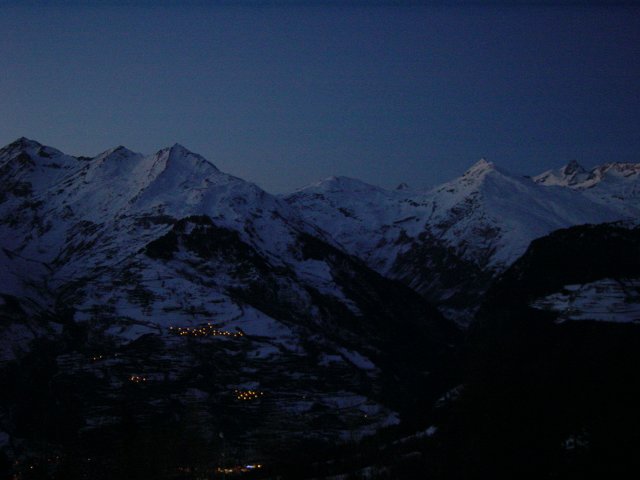 Luminosite bleutee sur les monts enneiges, quelques lumieres de villages