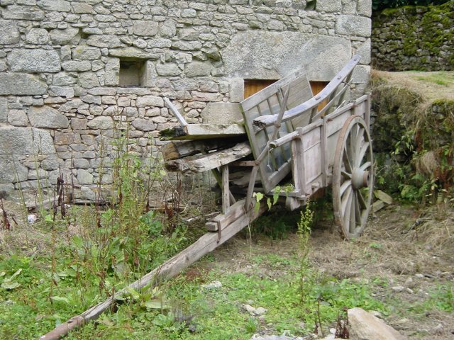 Charrette remplie de planches entre la maison et le puits