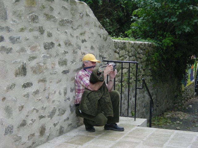 Papa accroupit contre un mur prenant une photo