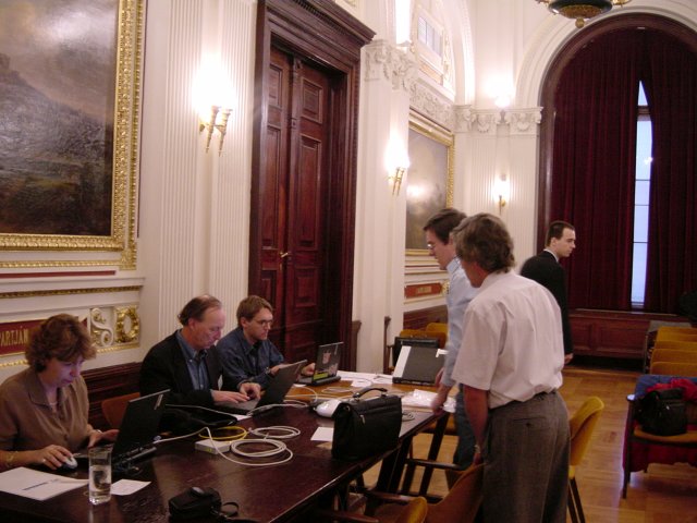 Marie-Claire, Vincent, Max, at the laptop table, two people stangind in front of them, among them the system guy