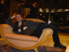 Max elegantly sprawled on a large armchai in the hotel lobby