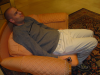 Deandroid sitting rigidly in an armchair