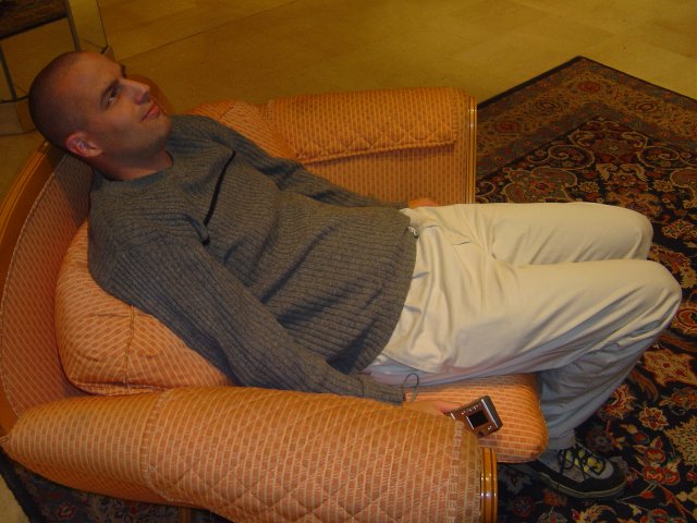 Deandroid sitting rigidly in an armchair
