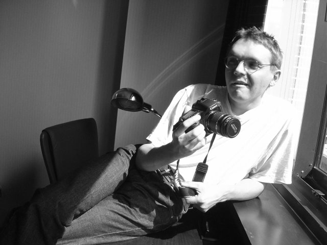 Maxf posing with his camera by the window, in the sunlight