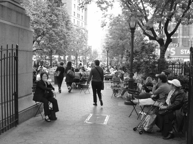 Marie-Claire enters some terrace with trees, tables and chairs