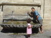 Steph se desaltere a une fontaine sous le regard intrigue' d'une petite fille