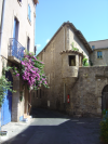 Maison blanche a volets bleus, bougainvillee mauve et vieille batisse