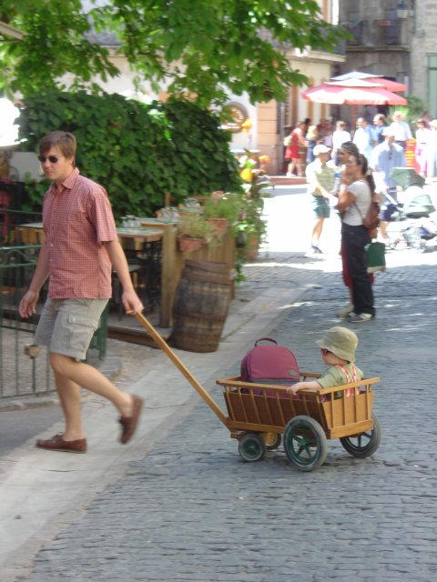 Un papa trainant une cariole contenant son fils
