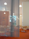 Behind a metallic curtain, tables and chairs in the restaurant area