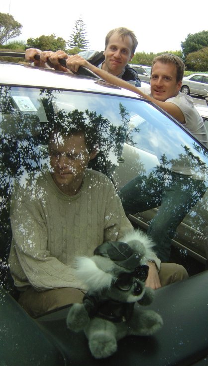 Joel, stuffed koala in the car, Nico and Fabrice goofing around