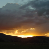 The sun burns as it sets behind black hills