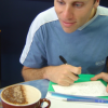 Nico writing postcards and eyeing a hot cocoa intently