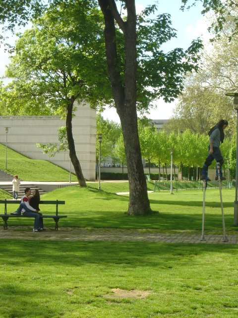 Man on stilts, couple on a bench