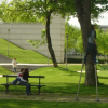 Lovers facing each other on a bench, unfazed as a man passes by them on stilts
